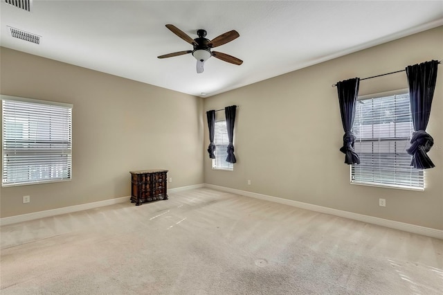 unfurnished room with a wealth of natural light, ceiling fan, and light carpet