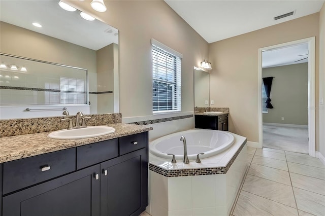 bathroom with tile patterned flooring, vanity, and tiled tub