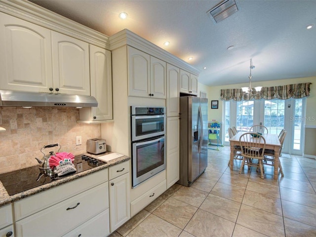 kitchen with appliances with stainless steel finishes, backsplash, light stone countertops, light tile patterned floors, and a notable chandelier