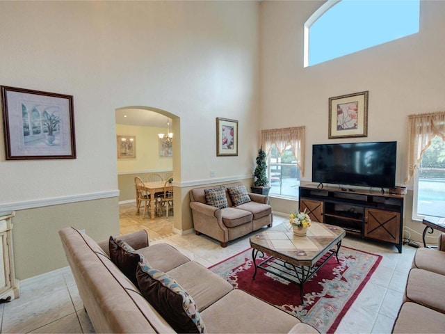 living room featuring light tile patterned floors, a towering ceiling, and a chandelier