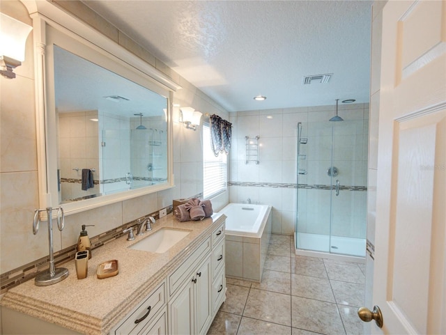 bathroom featuring a textured ceiling, tile patterned flooring, vanity, and plus walk in shower