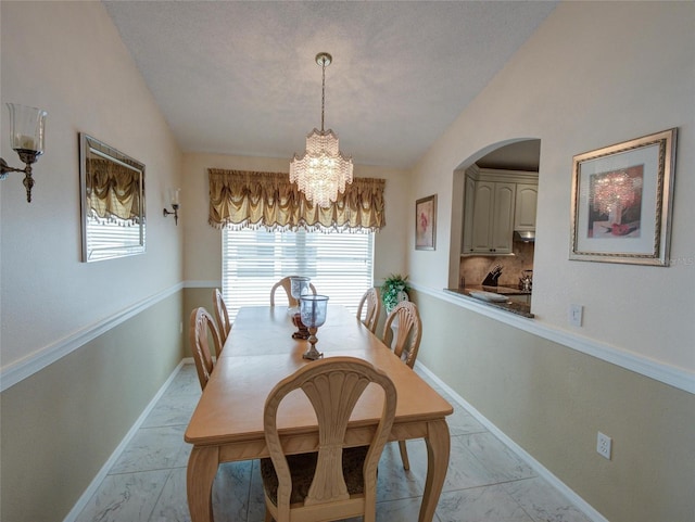 dining area featuring an inviting chandelier, lofted ceiling, and a textured ceiling