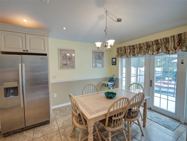 tiled dining area featuring a textured ceiling and a chandelier