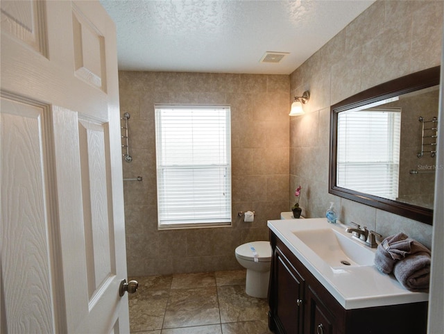 bathroom featuring tile walls, tile patterned flooring, a textured ceiling, vanity, and toilet