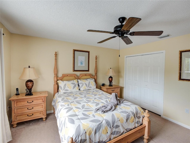 bedroom featuring a closet, ceiling fan, light colored carpet, and a textured ceiling