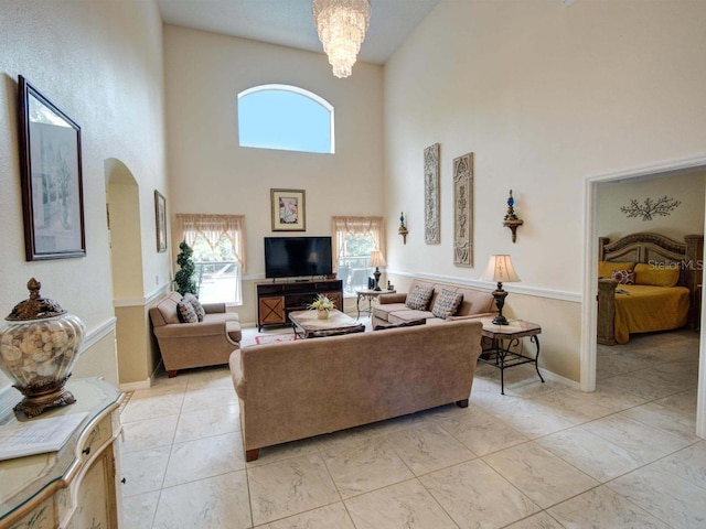 living room featuring a towering ceiling, a chandelier, and a wealth of natural light