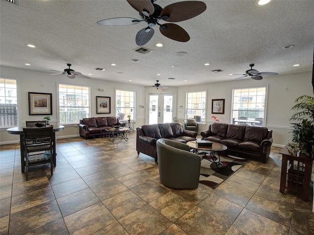 living room featuring a textured ceiling, ceiling fan, and plenty of natural light