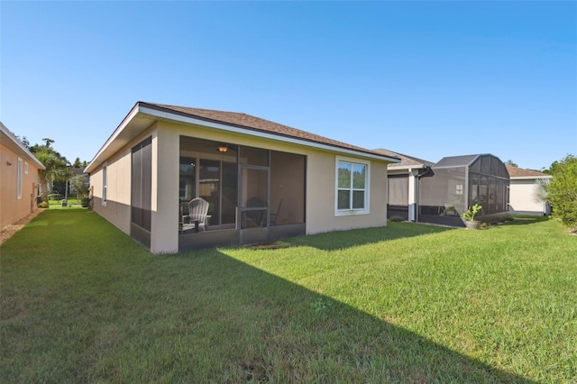 rear view of property featuring a sunroom, glass enclosure, and a yard