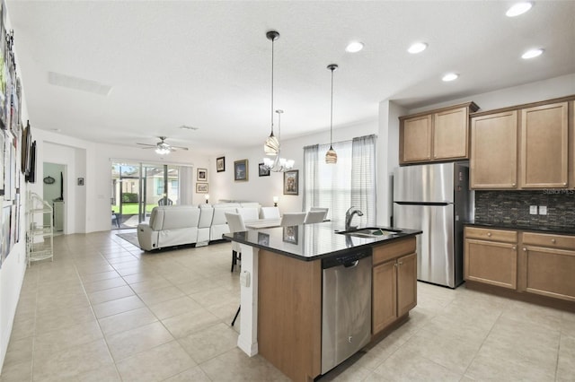 kitchen with a kitchen island with sink, ceiling fan with notable chandelier, hanging light fixtures, appliances with stainless steel finishes, and light tile patterned floors