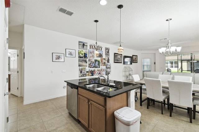 kitchen with pendant lighting, sink, a kitchen island with sink, dishwasher, and a notable chandelier