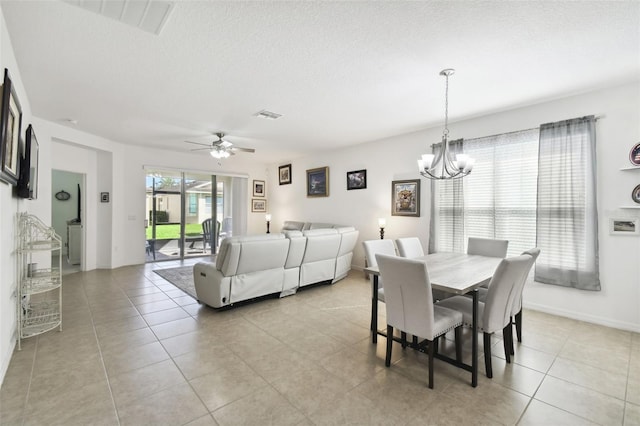 tiled dining area featuring a textured ceiling and ceiling fan with notable chandelier