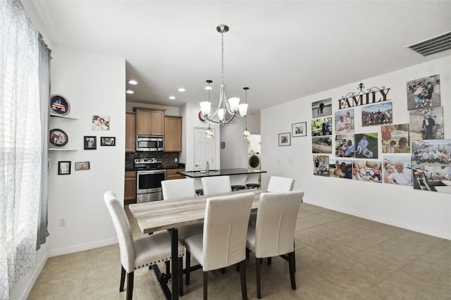 dining space featuring washer / clothes dryer, sink, dark tile patterned flooring, and a chandelier