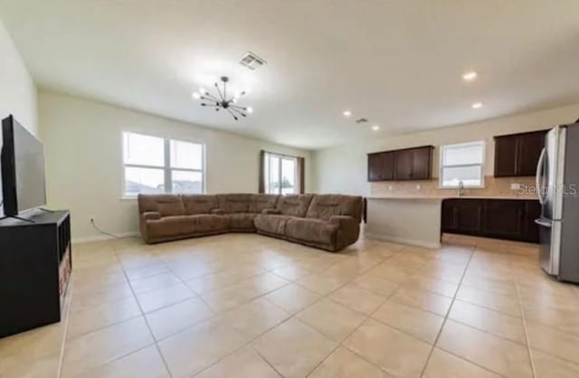 living room featuring light tile patterned flooring, sink, and a notable chandelier