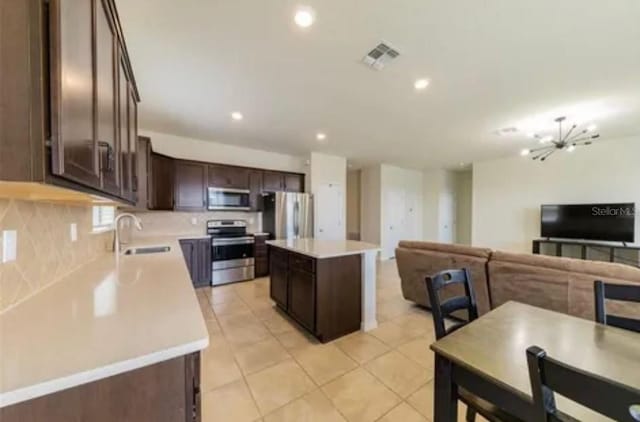 kitchen with dark brown cabinetry, sink, a kitchen island, stainless steel appliances, and decorative backsplash