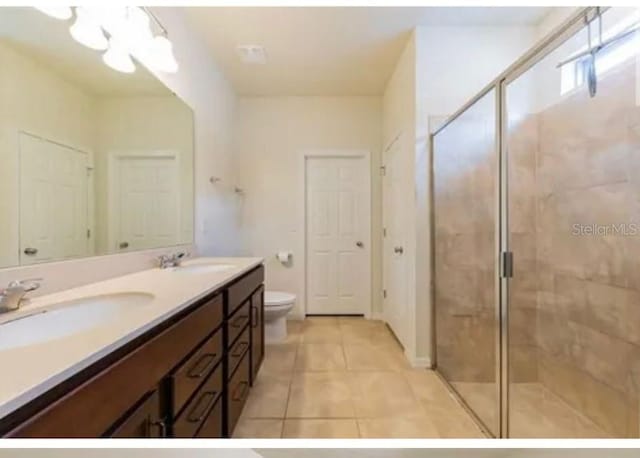 bathroom featuring tile patterned flooring, vanity, toilet, and a shower with door