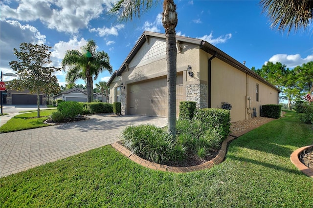 341 Navarra Ln, Davenport, FL 33837 - view of home's exterior with stone siding, a lawn, a garage, stucco siding, and driveway
