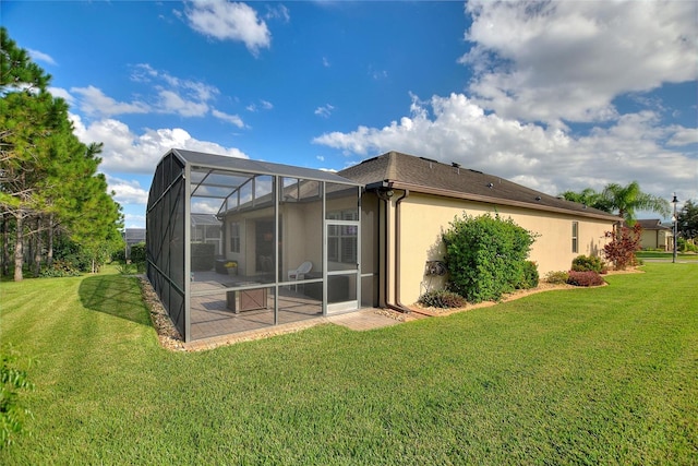 back of property with a yard, glass enclosure, and a patio area