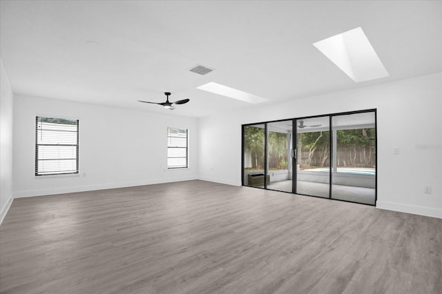 unfurnished room with wood-type flooring, a skylight, plenty of natural light, and ceiling fan