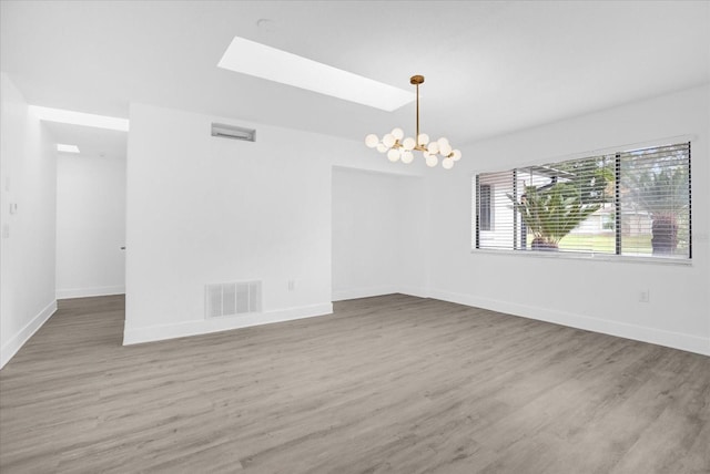 empty room featuring a skylight, hardwood / wood-style flooring, and a chandelier