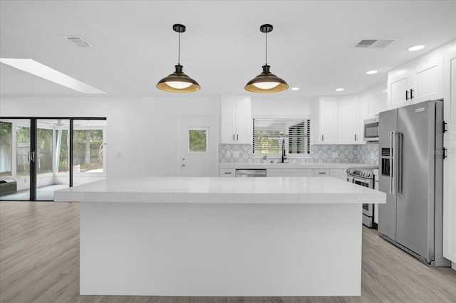 kitchen featuring light hardwood / wood-style flooring, a kitchen island, appliances with stainless steel finishes, and white cabinetry