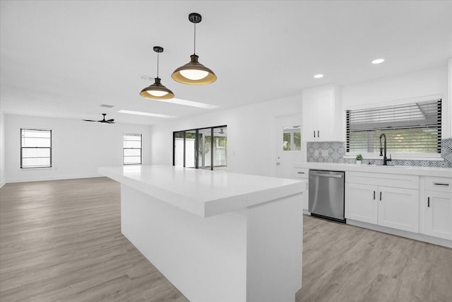 kitchen featuring hanging light fixtures, white cabinetry, plenty of natural light, and stainless steel dishwasher