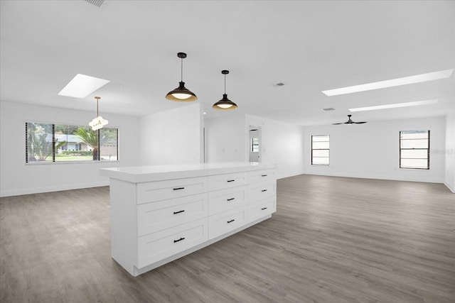 unfurnished living room featuring a skylight, hardwood / wood-style flooring, and ceiling fan