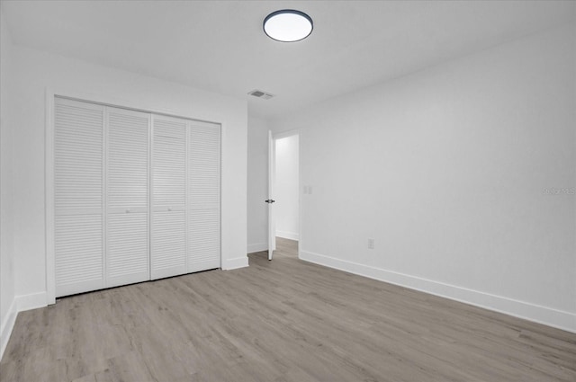 unfurnished bedroom with light hardwood / wood-style flooring and a closet