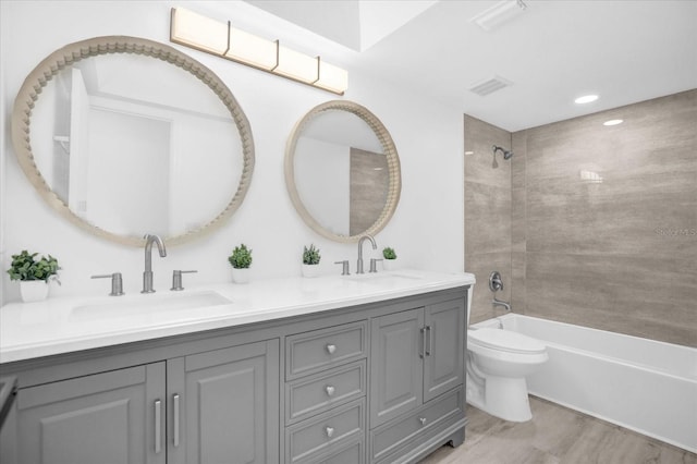 full bathroom featuring vanity, tiled shower / bath combo, and toilet