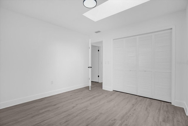 unfurnished bedroom with a closet, light wood-type flooring, and a skylight