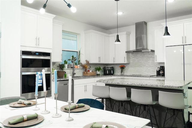 kitchen featuring white cabinets, wall chimney exhaust hood, and a kitchen island