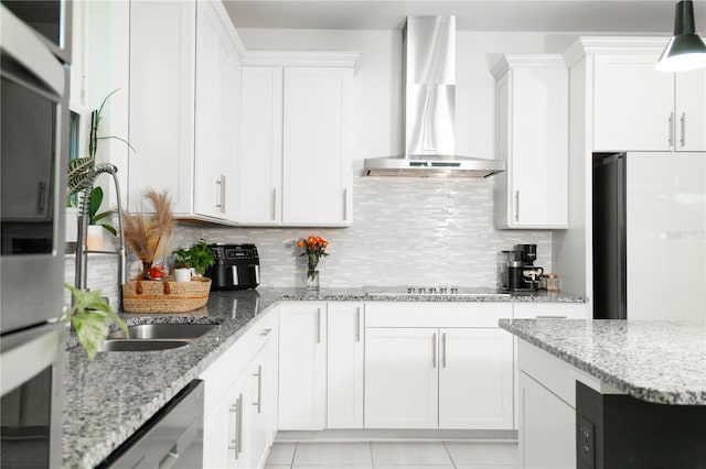 kitchen with appliances with stainless steel finishes, backsplash, wall chimney exhaust hood, and white cabinetry