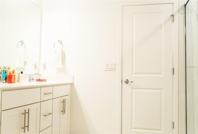 bathroom featuring a shower with door and vanity