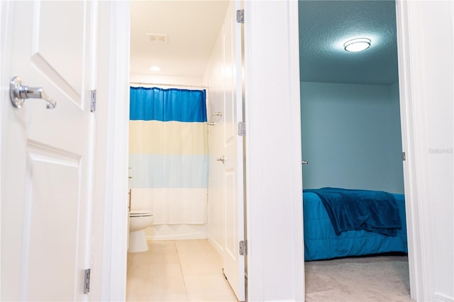 bathroom featuring tile patterned flooring, a textured ceiling, and toilet