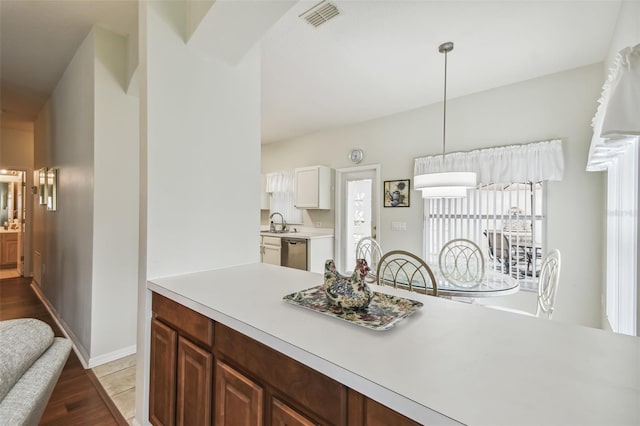 kitchen featuring sink, dishwasher, light hardwood / wood-style flooring, and decorative light fixtures