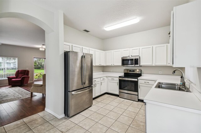 kitchen with light hardwood / wood-style flooring, appliances with stainless steel finishes, sink, and white cabinets