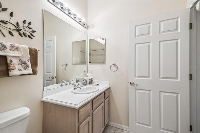 bathroom with toilet, vanity, and tile patterned flooring