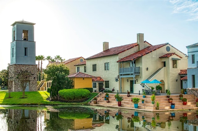 rear view of property with a yard and a balcony