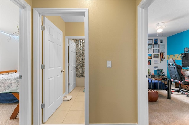 hallway with light carpet and a textured ceiling