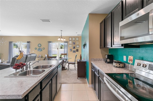 kitchen with pendant lighting, light tile patterned floors, a kitchen island with sink, a chandelier, and stainless steel appliances