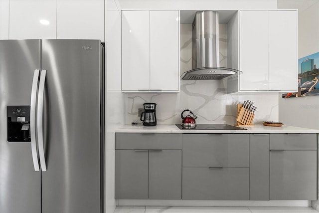 kitchen featuring stainless steel fridge, gray cabinetry, wall chimney exhaust hood, white cabinetry, and black electric stovetop