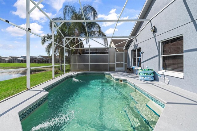 view of pool with glass enclosure, a water view, and a patio