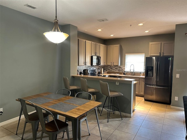 kitchen featuring light tile patterned flooring, sink, kitchen peninsula, hanging light fixtures, and appliances with stainless steel finishes