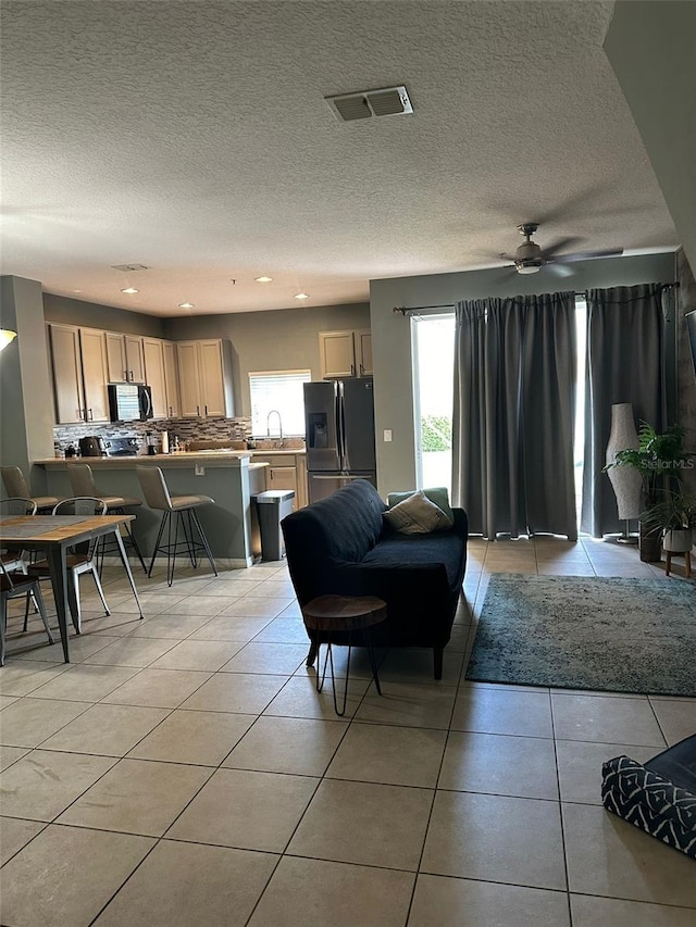 tiled living room with ceiling fan, sink, and a textured ceiling