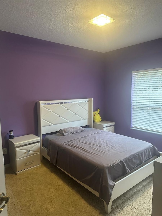 bedroom with light colored carpet and a textured ceiling