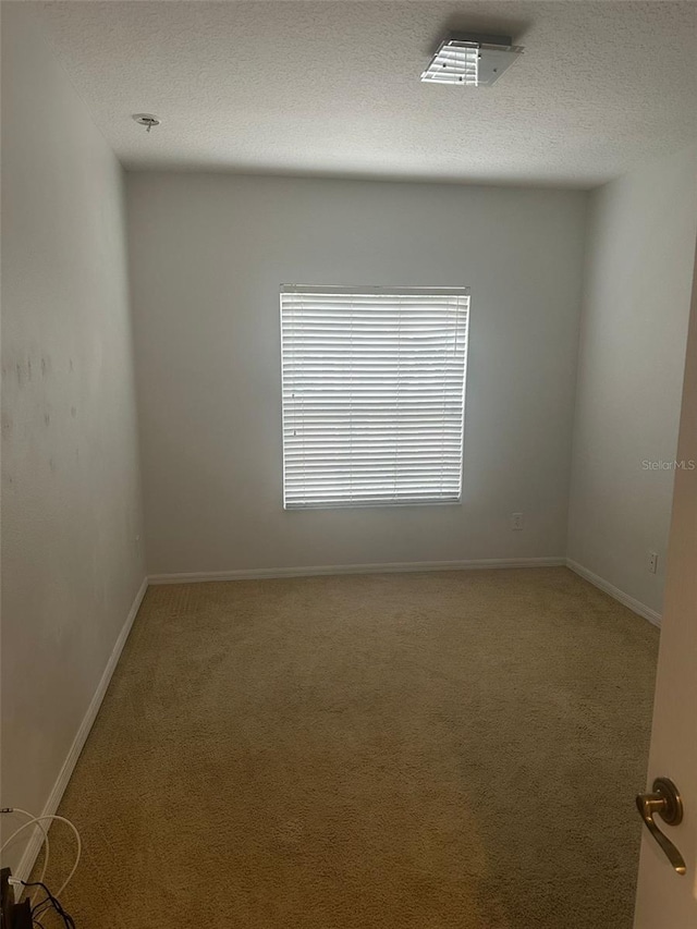 carpeted empty room with a textured ceiling