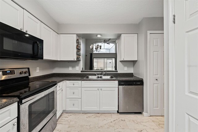 kitchen with dark stone countertops, white cabinetry, stainless steel appliances, a textured ceiling, and sink