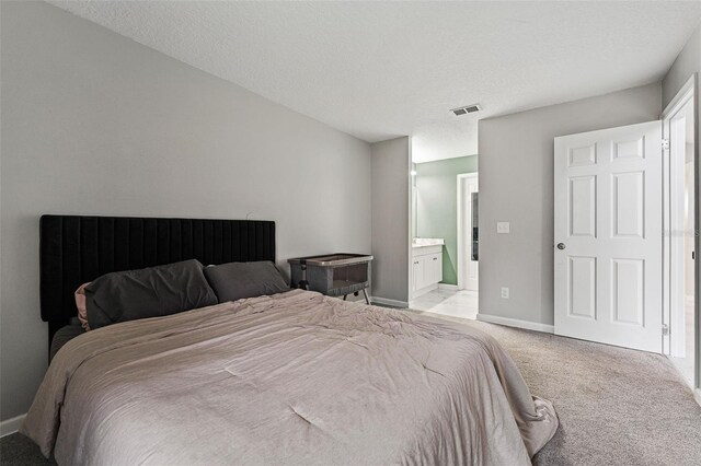 carpeted bedroom with a textured ceiling and ensuite bath