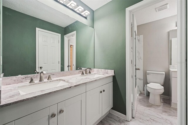 bathroom featuring vanity, toilet, and a textured ceiling