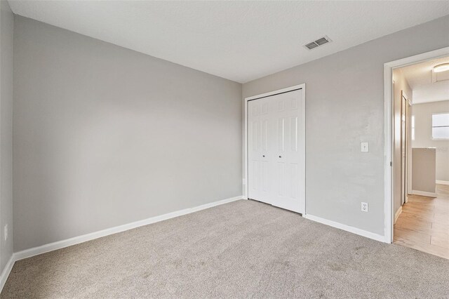 unfurnished bedroom featuring a closet and light colored carpet