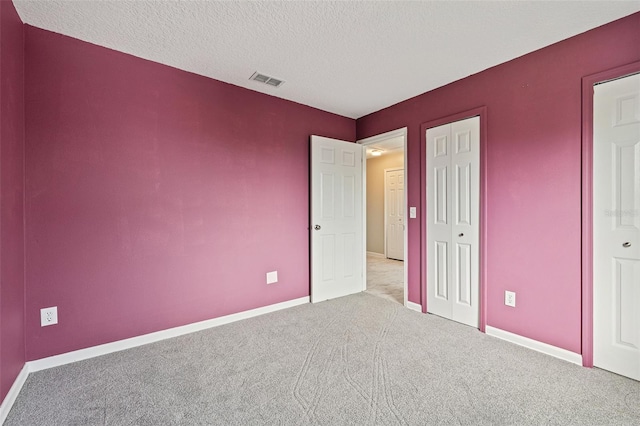 unfurnished bedroom with a textured ceiling and light colored carpet